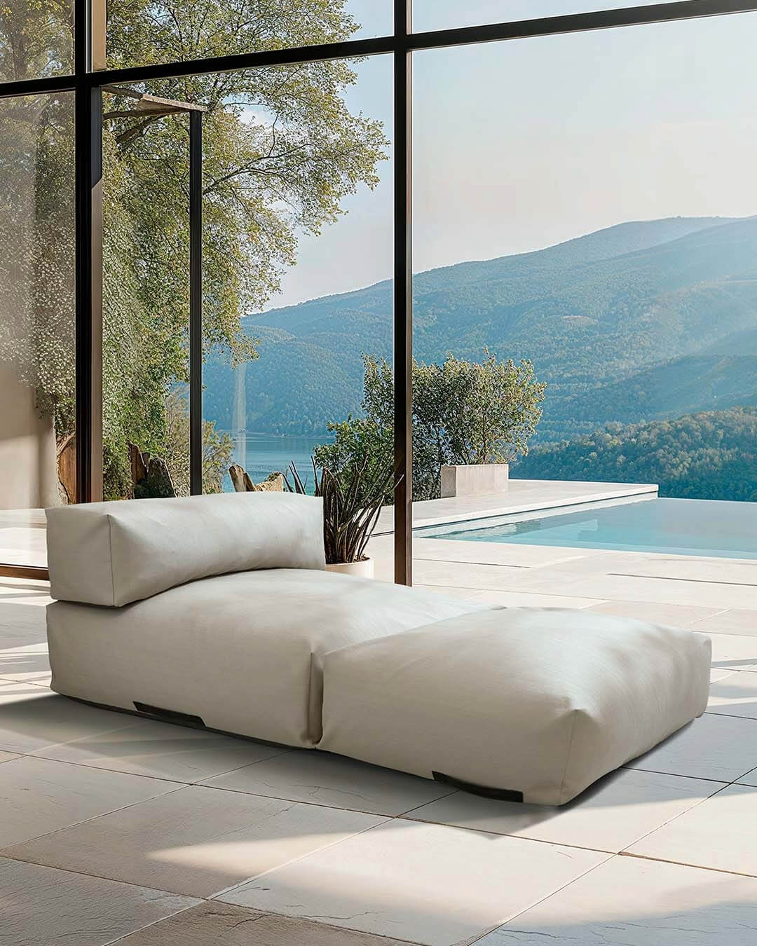 Ein Poolsofa Double in Beige steht in einem Wohnzimmer, die Terrassentür steht offen und der Blick geht auf eine Terrasse mit Pool. $ Poolsofa Double | Beige