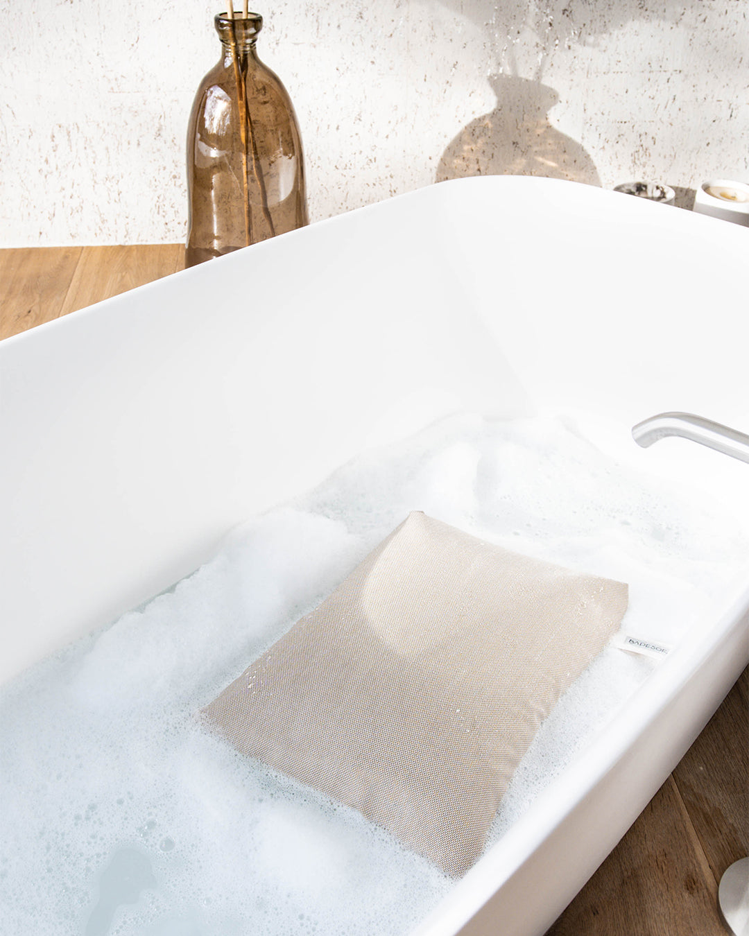 Badesofa Sitzkissen (Farbe Perlmutt) liegt in einer tiefen freistehenden Badewanne.