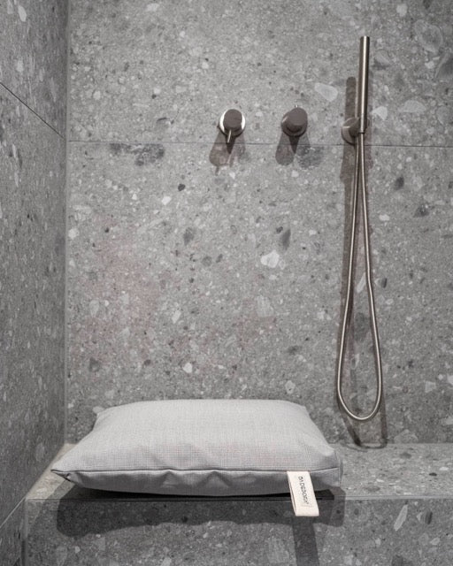 Nahaufnahme des Badesofa Sitzkissen (Farbe: Grau) auf einer gemauerten Bank in der Dusche. 