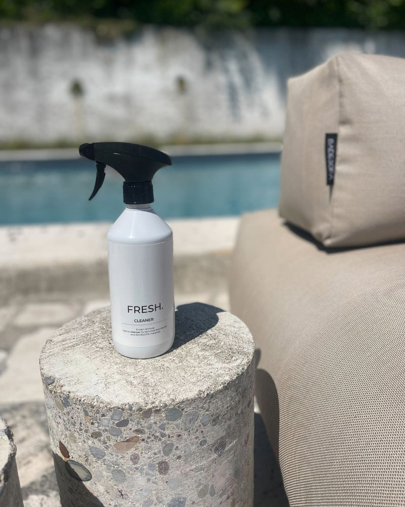 Reinigungsspray steht neben einem Poolsofa. 